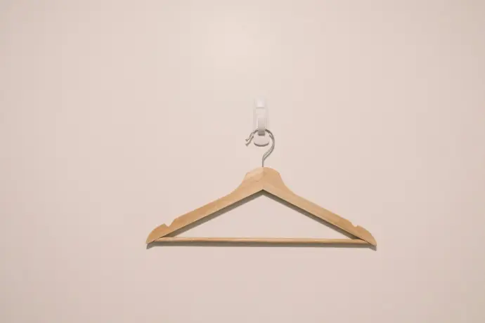 a wooden hanger with a hook on a white wall
